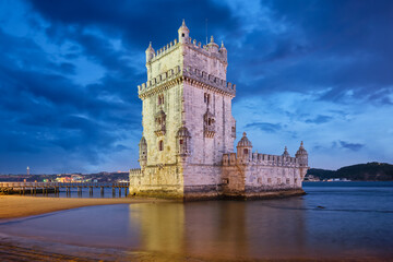 Naklejka premium Belem Tower or Tower of St Vincent - famous tourist landmark of Lisboa and tourism attraction - on the bank of the Tagus River Tejo after sunset in dusk twilight with dramatic sky. Lisbon, Portugal