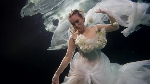 mysterious bride in wedding dress swimming underwater, slow motion shot, romantic fairytale