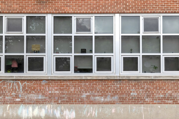 Facade of an old red brick public school building brick walls, chalk marks, white-paned windows,...