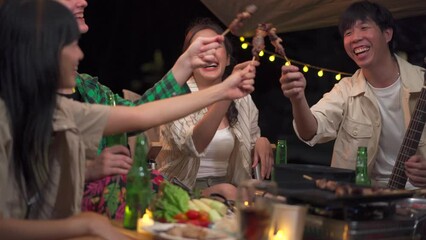 Group of diverse ethnicity young people enjoy eating and grilling bar-b-q together while camping in forest at night. - Powered by Adobe