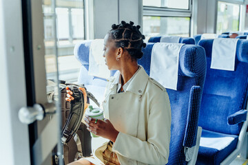 Thoughtful african young woman traveler with a backpack took a seat in the train car.