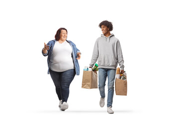 Full length portrait of an american african young man with grocery bags walking with a corpulent...