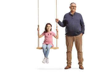 Grandfather standing next to girl on a wooden swing
