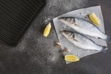 Fresh seabass and ingredients for cooking on a black background.