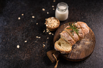 Sliced artisan baguette bread on wooden coaster and rustic background. Sourdough bread.