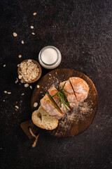 Obraz na płótnie Canvas Sliced artisan baguette bread on wooden coaster and rustic background. Sourdough bread.