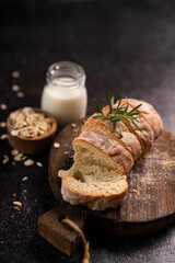 Sliced artisan baguette bread on wooden coaster and rustic background. Sourdough bread.