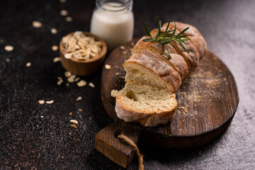 Sliced artisan baguette bread on wooden coaster and rustic background. Sourdough bread.