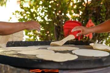 Anonymous cooks frying Mexican flatbreads in nature