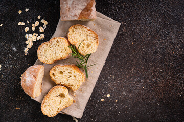Sliced artisan baguette bread on wooden coaster and rustic background. Sourdough bread.