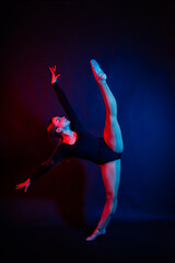 Obraz premium A girl gymnast in a swimsuit does tricks on a white and dark background. Front view