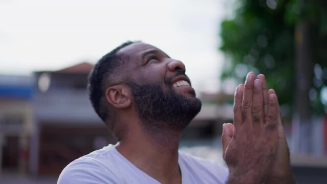 Grateful African American man thanking God, looking up at sky in prayer and smile. One happy black Brazilian man gazing upwards with HOPE and FAITH