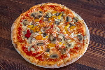 Funghi pizza with tomato sauce, cheese, mushrooms, peppers and corn on wooden table