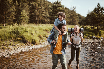 Young family crossing a creek and hiking in the forest