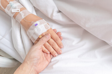 close up man holding his lover hand with love and care while sick on patient bed in hospital - 618608946