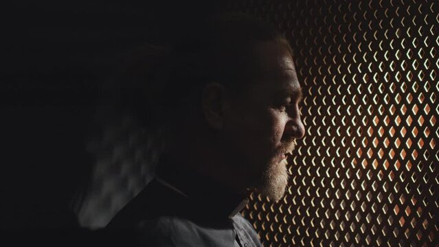 Side view close-up of mature Catholic priest working in confessional helping repentant with advice