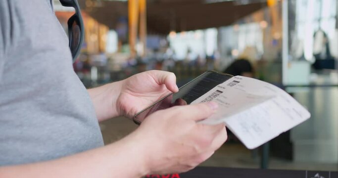 Freelancer at airport check-in desk answers messages on phone. Freelancer traveler bought tickets to another country. Concept: freelancer with tickets to the flight can work from anywhere in the world