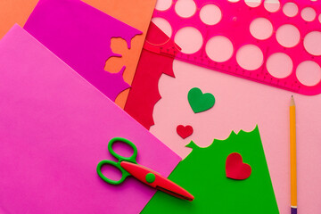 Children's workplace for making crafts. Cutting multi-colored hearts from foamiran. Children's stationery: scissors, ruler, pencils and marker.