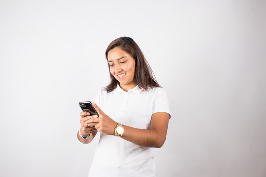 Photograph Of Latina Woman Using Cell Phone On A Photo Studio Background. Concept Of People And Technology.