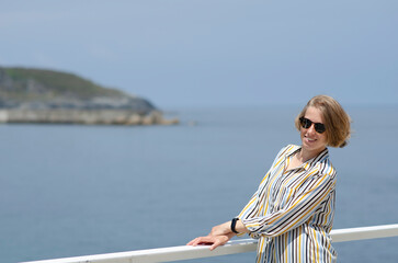 Fototapeta premium Young Woman Smiling On a Sunny Day at The Seaside with Coastal View in the Background