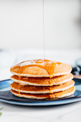 Fresh American Pancakes with maple syrup on blue plate
