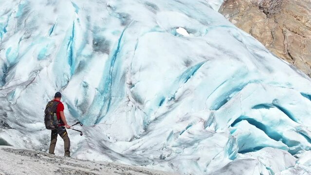 Caucasian Hiker in His 40s Staying Next to Kjenndal Glacier in the Vestland County Norway. Windy Conditions.