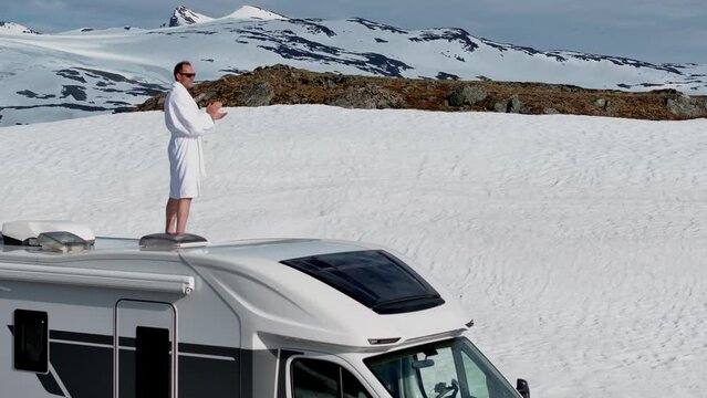 Funny Tourist in Bathrobe Staying on a Roof of His Motorhome and Exciting the View