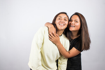 Portrait of two young women embracing on a white studio background. Concept of people.