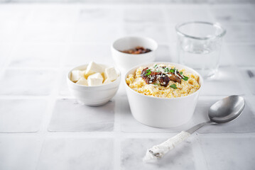 Corn porridge with fried bacon, parsley and Feta cheese in a bowl