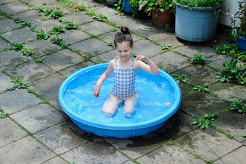 Cute girl playing in the shallow pool in the backyard