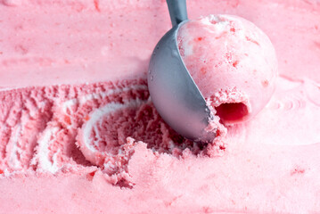 Fototapeta na wymiar Pink strawberry ice cream is scooped up with a spoon