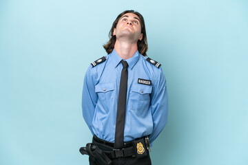 Young police caucasian man isolated on blue background and looking up