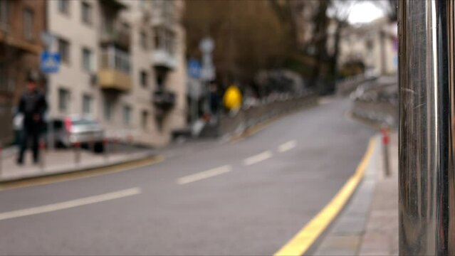 Hilly street in the city with walking pedestrians out of focus. Static picture of a beautiful city in defocus