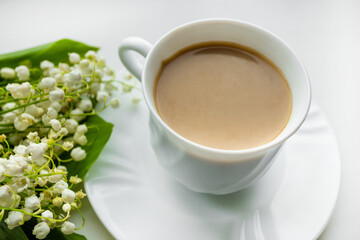 Coffee mug with a bouquet of flowers lily of the valley. View from above, the concept of morning.