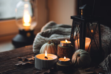 Cozy autumn composition with aromatic candle, pumpkins, wool sweater, leaves, cinnamon....