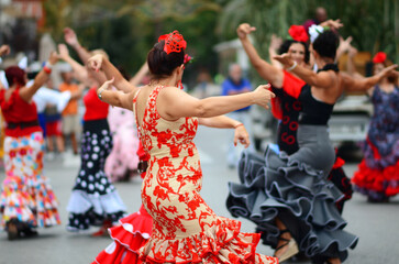 Women dancing back to back wearing flamenco style clothing at the Spanish Romeria festival - obrazy, fototapety, plakaty