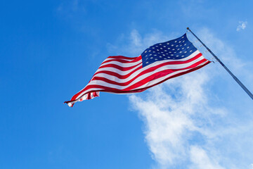 Fototapeta premium American Flag blowing in the wind with a blue sky, USA American Flag. Waving United states of America famous flag in front of blue sky. Independence Day, Labor day, Flag Day - American Celebration