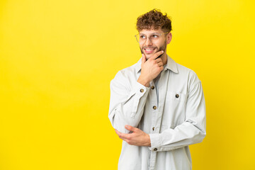 Young handsome caucasian man isolated on yellow background thinking an idea while looking up