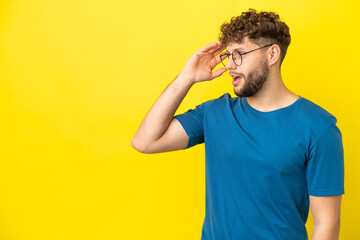 Young handsome caucasian man isolated on yellow background with surprise expression while looking side