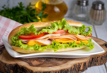 Cheese, ham, lettuce and tomato slices in an appetizing tasty sandwich.