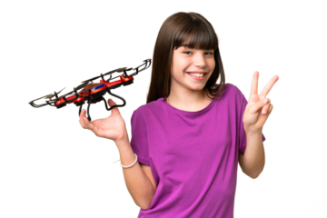 Little caucasian girl holding a drone over isolated background smiling and showing victory sign