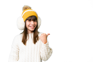 Little caucasian girl wearing winter muffs over isolated background pointing to the side to present a product