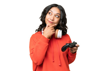 Young Argentinian woman playing with a video game controller over isolated background and looking up © luismolinero