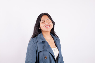Portrait of latina woman smiling with eyes close on light background of photo studio. Concept of people.