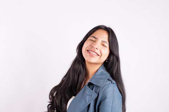 Portrait of latina woman smiling with eyes close on light background of photo studio. Concept of people.