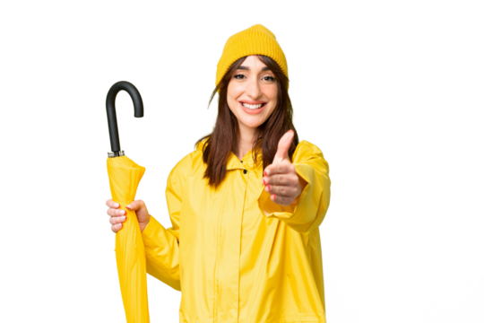 Young caucasian woman with rainproof coat and umbrella over isolated chroma key background shaking hands for closing a good deal