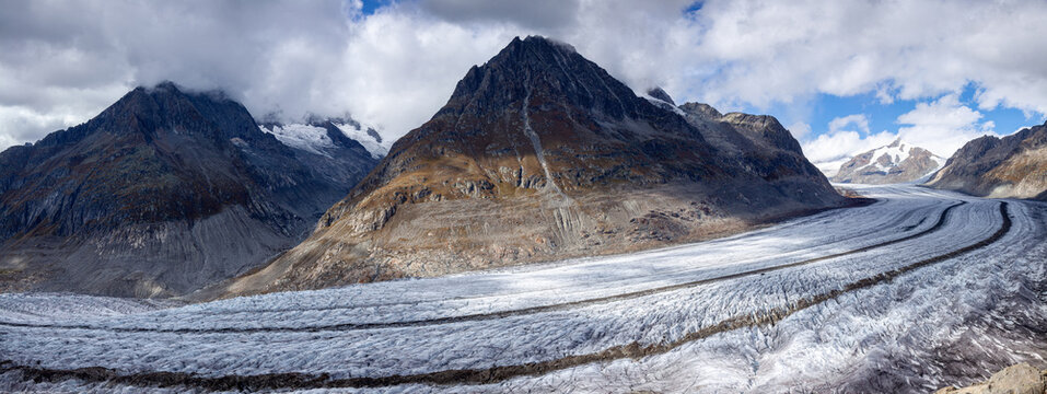 Panoramic photo of the Aletch Glacier in the Swiss Alps. Huge blocks of ice against the backdrop of the mountains Olmenhorn and Gaeisshorn in Switzerland