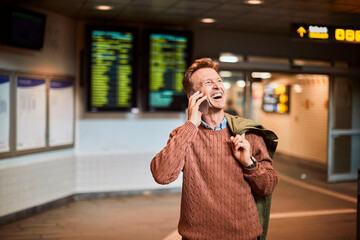 Mature man talking on the phone while waiting at the train station