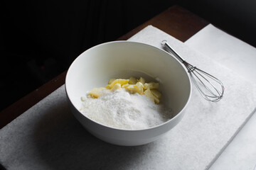 cubes of butter and sugar in a white bowl, organic butter and granulated sugar about to be creamed in a white mixing bowl, process of making cake
