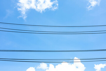 Power lines under clouds blue sky. Electric cable stripes with a beautiful bright sky above the ground. Electricity industry against nature, abstract background concept.